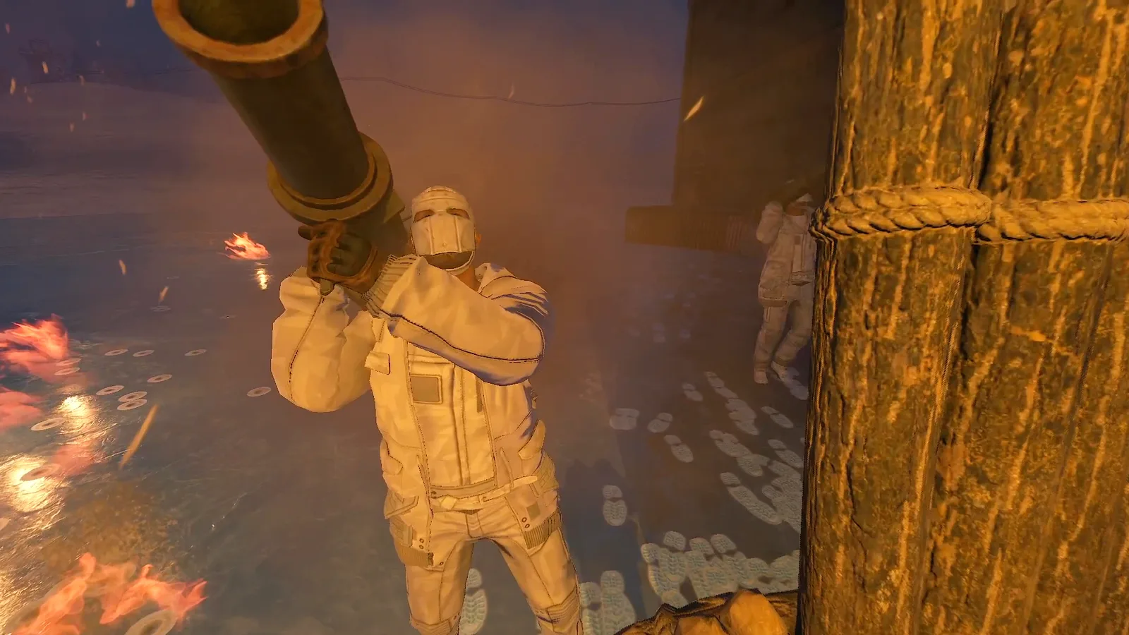A raider in white arctic gear shoulders a rocket launcher behind the raid base's wooden palisade, with fires burning on the ice around him.